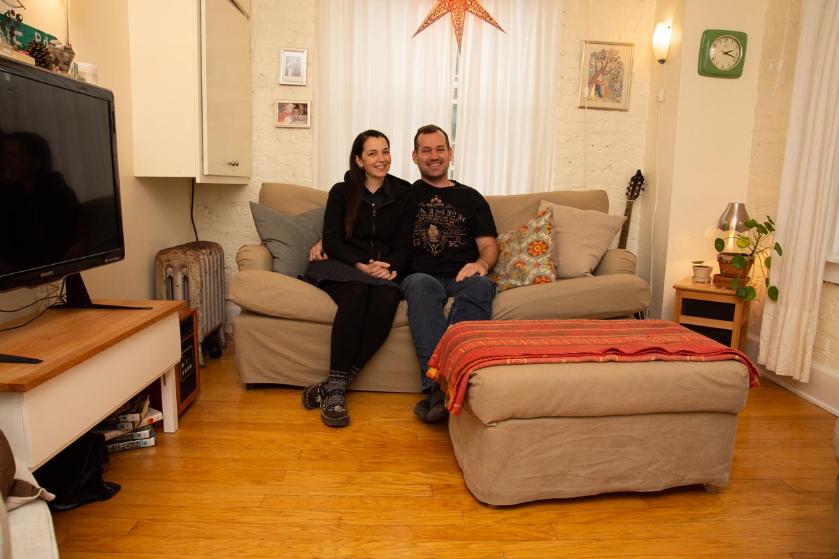 A couple sitting on their couch in their small apartment