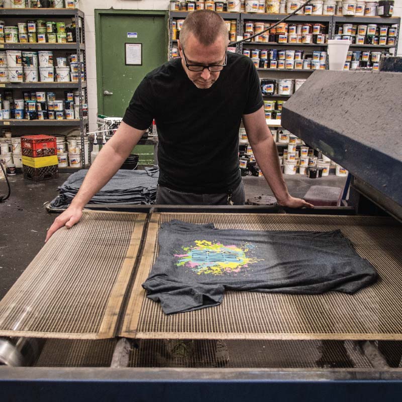 A person screen printing t-shirts